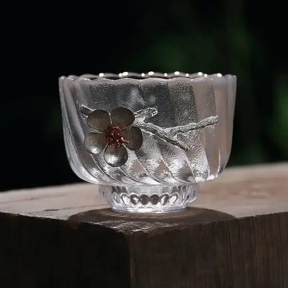 Elegant carved tin glass tea cup set featuring a clear frosted glass cup with embossed cherry blossom design in dark gray metal