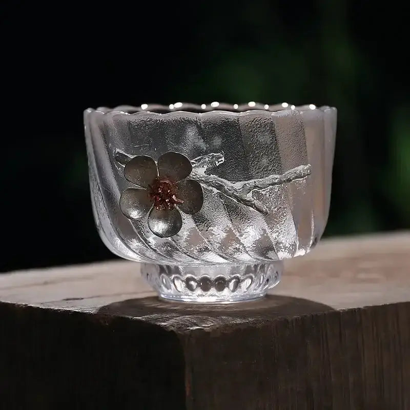 Elegant carved tin glass tea cup set featuring a clear frosted glass cup with embossed cherry blossom design in dark gray metal