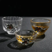 Elegant carved tin glass tea cup set with dark floral embellishments and textured rims holding amber tea