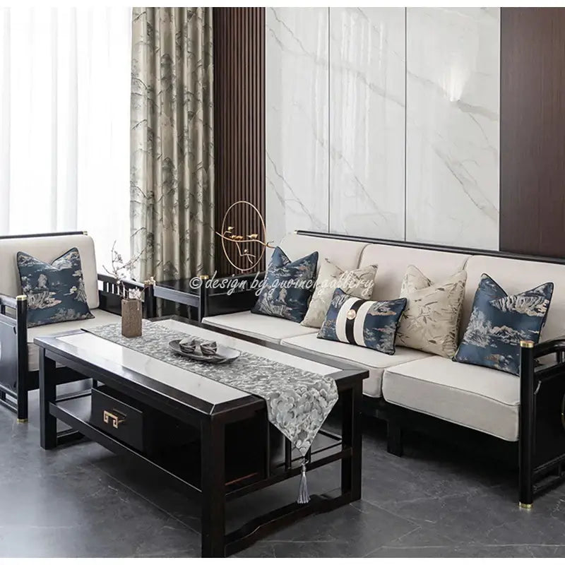 Black wooden coffee table with white marble top and silver tassel runner next to elegant cream dragonfly insects embroidery cushion cover