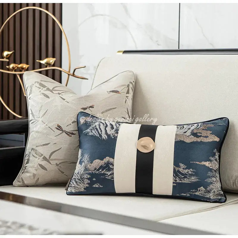 Elegant navy blue cushion with intricate mountain and bird embroidery featuring a bold cream stripe band and gold button decorbites dragonfly insects