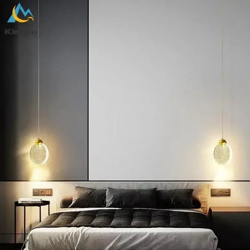 Two gold-toned decorbites elegant crystal led pendant lights with textured glass globes hang above a modern bed