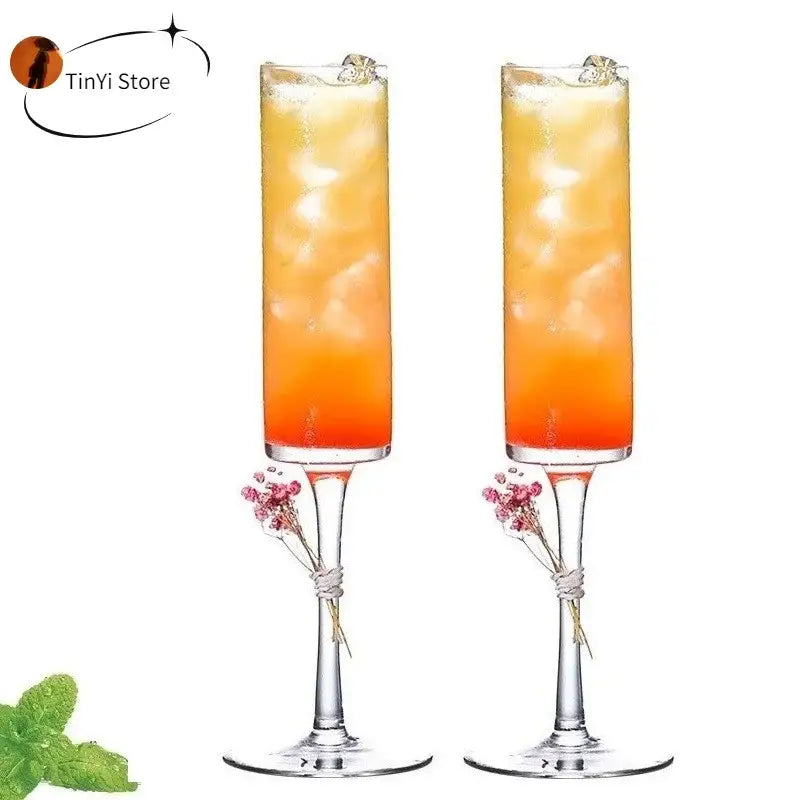Two clear glass decorbites bubble champagne glasses with dried pink flower bundles on the stems for elegant dining