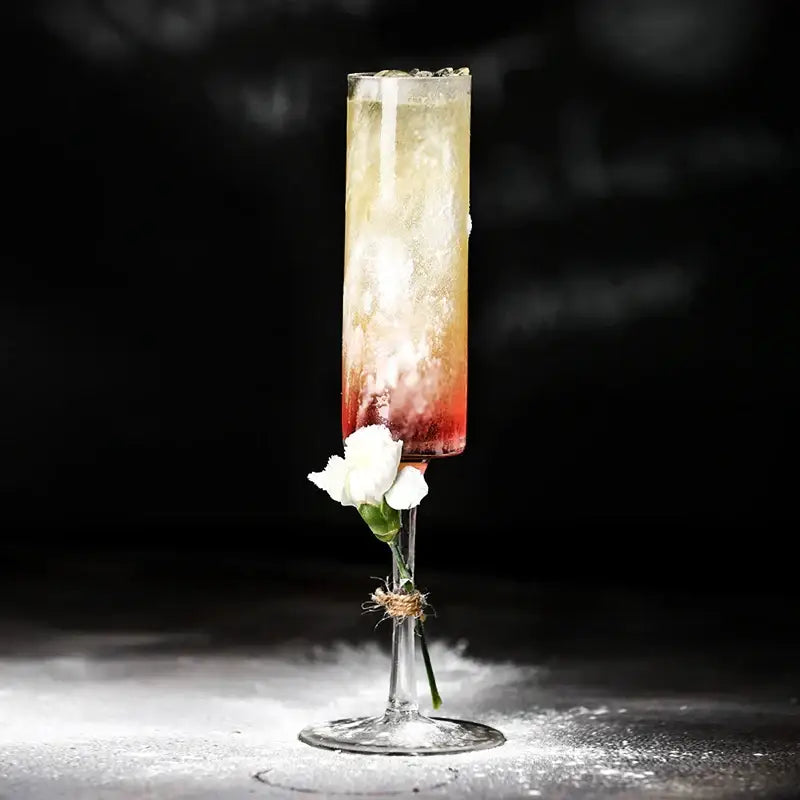 A slender bubble champagne glass filled with a red to pale yellow layered cocktail from decorbites set of 2