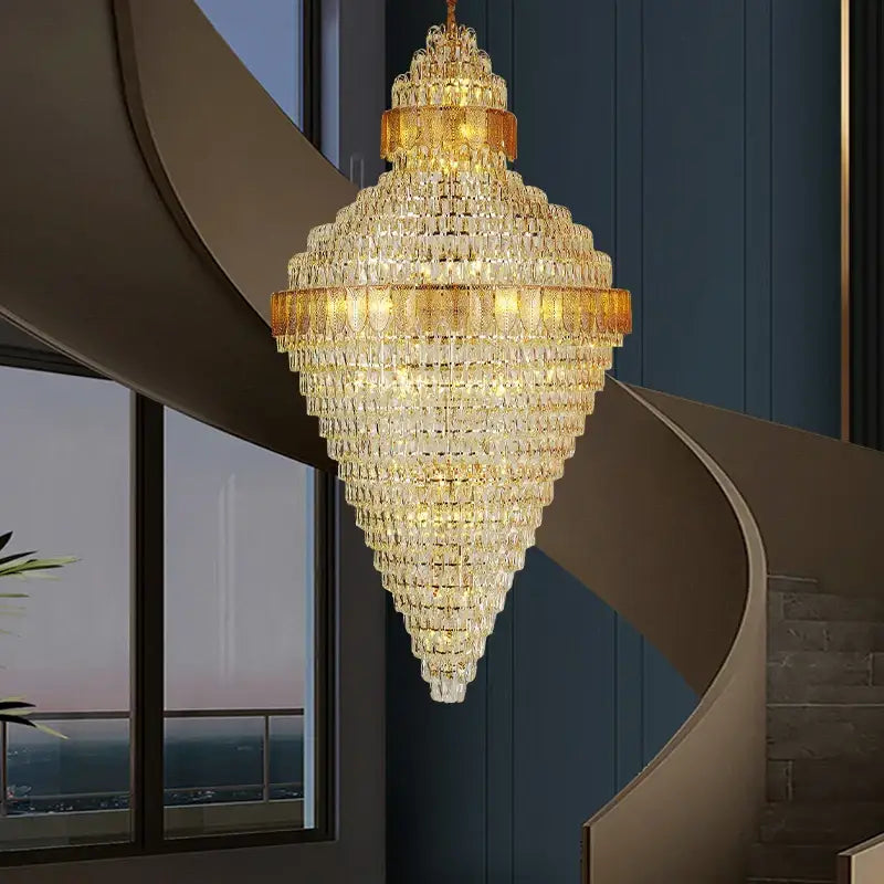 A luxurious decorbites elegant duplex crystal chandelier with gold and amber tones above a modern staircase