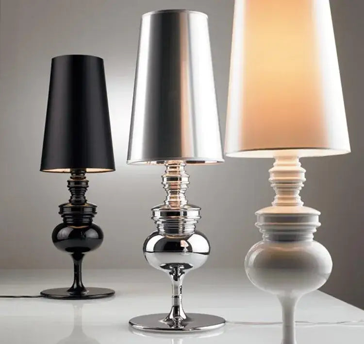 Three elegant european style bedside lamps with sleek reflective bases and tapered black silver and off-white shades