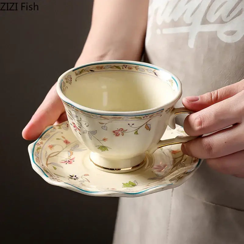 Cream-colored elegant floral ceramic cup and saucer set with soft pink green and gold accents for dining room use