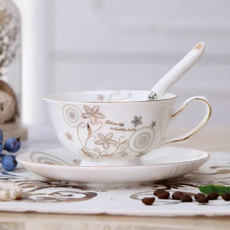 White porcelain tea cup set with gold and beige floral patterns and gold trim resting on matching saucer