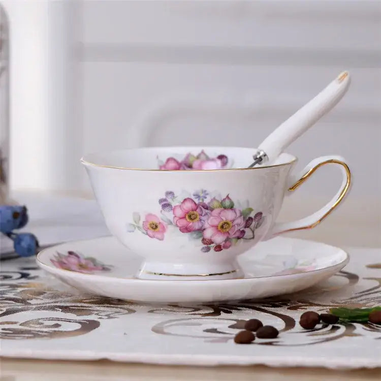 Elegant floral porcelain tea cup set featuring a white cup with pink purple flowers and gold trim on rim and handle