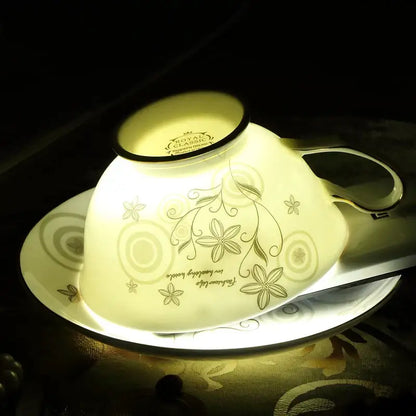 Elegant floral porcelain tea cup set in cream with gold trim and vine patterns resting on a matching saucer