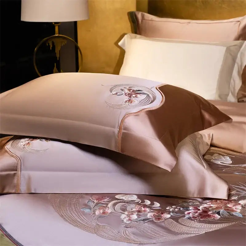 A blush pink satin pillowcase with elegant flowers embroidery in rose gold featuring a brown satin accent panel