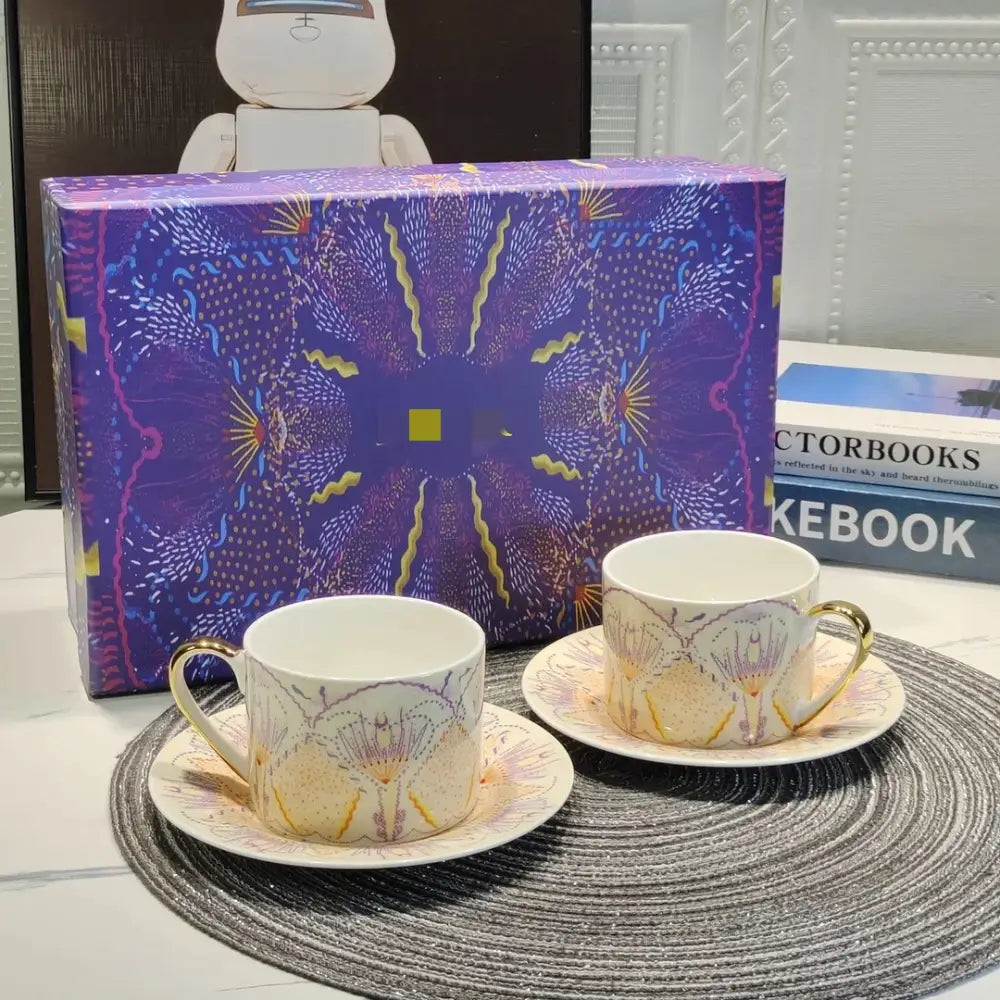 A bone china tea cup set with elegant gold handles and purple floral patterns presented with matching saucers and gift box