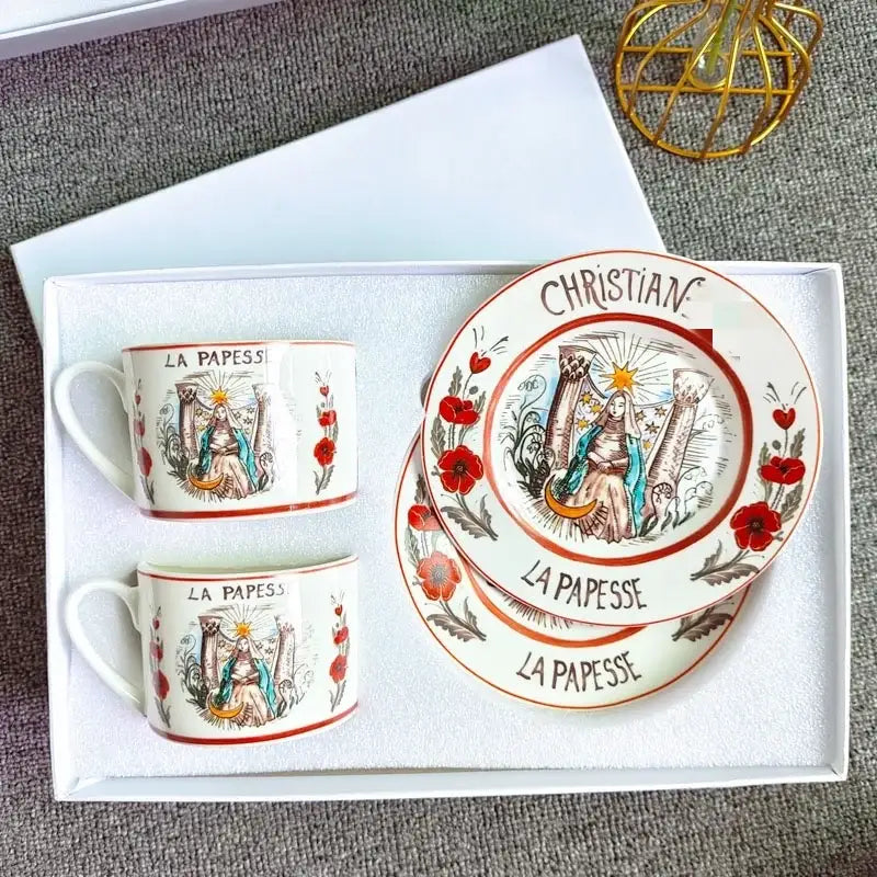 Elegant white bone china tea cup set with red floral border and hand-painted saintly figure in blue robes and sunburst design