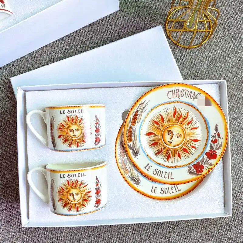 Elegant geometric bone china tea cup set in white with hand-painted orange and red sun motifs and le soleil text