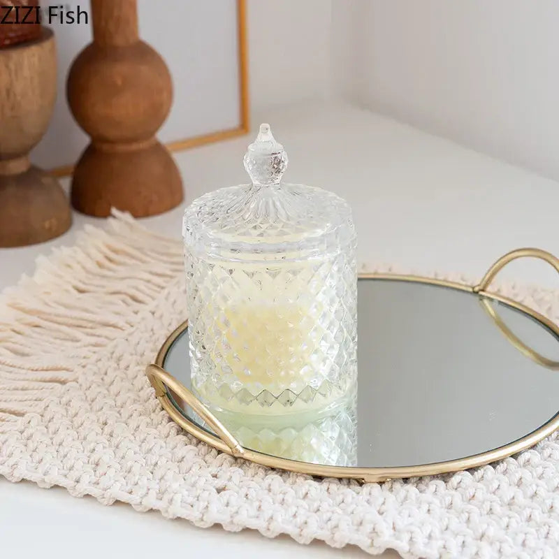 Clear glass candle jar with diamond-patterned design and crystal lid on elegant giraffe gold ceramic jar and brass handle storage tray