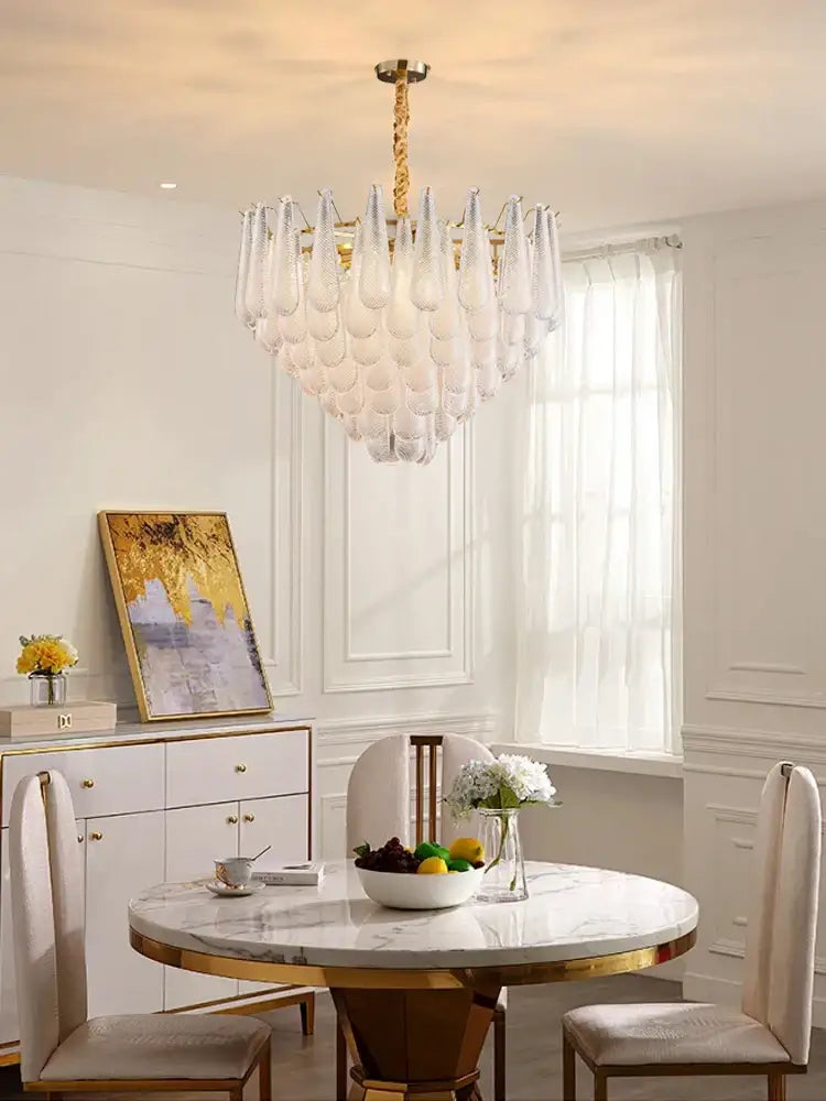 A decorbites elegant glass chandelier with gold tiered metal frame and teardrop glass shades for dining room lighting