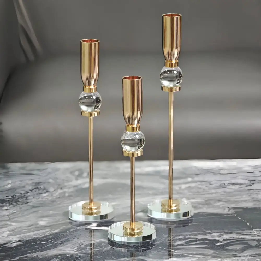 Set of three elegant gold-toned decorbites crystal glass candlestick holders with clear spheres and mirrored bases for dining room decor