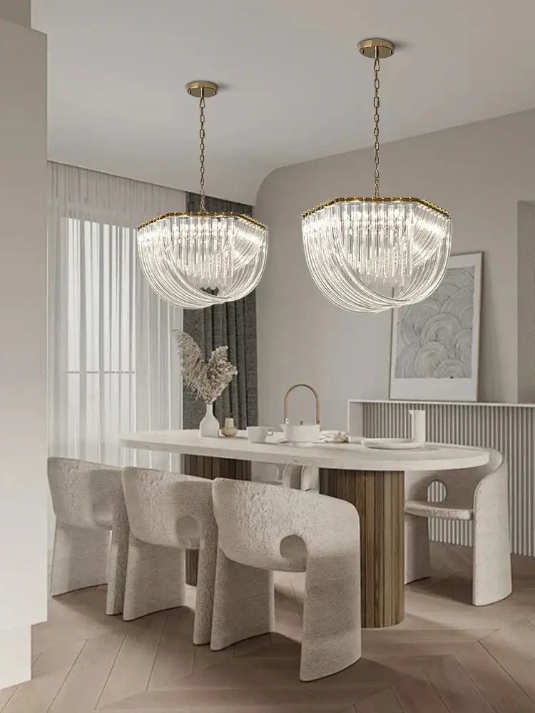 Two elegant gold and glass crystal pendant lights with cascading crystal strands hang above a kitchen island
