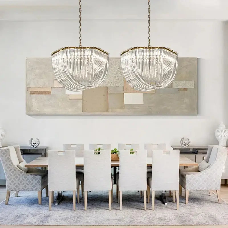 Two elegant gold and glass crystal pendant lights with metal frames hang above a dining table as pendant lights
