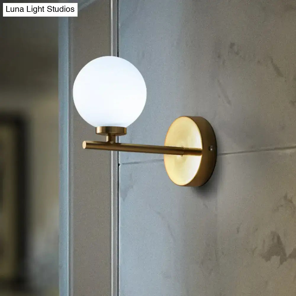 Elegant gold and ivory glass wall sconce with brass finish and frosted glass globe for bedroom wall light