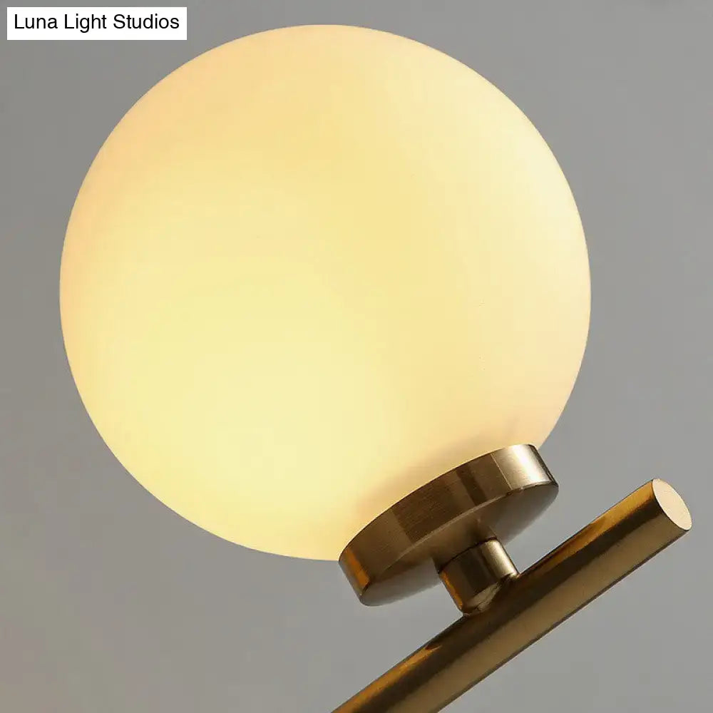 Elegant gold and ivory warm-toned frosted glass globe wall sconce with brass base for bedroom wall light design
