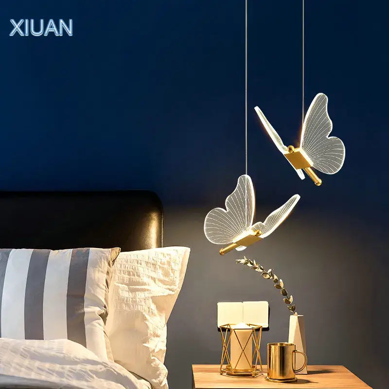 Two elegant translucent decorbites butterfly pendant lamps with gold-toned metal bodies hang from the ceiling