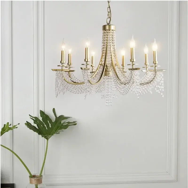 Elegant gold crystal candle chandelier with multiple arms and cascading clear droplets by decorbites for dining room decor