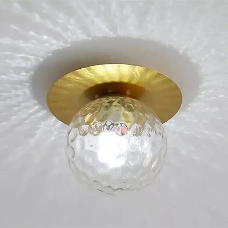 Elegant gold crystal ceiling light fixture with clear textured glass globe and hammered gold metal base for hallway entrance