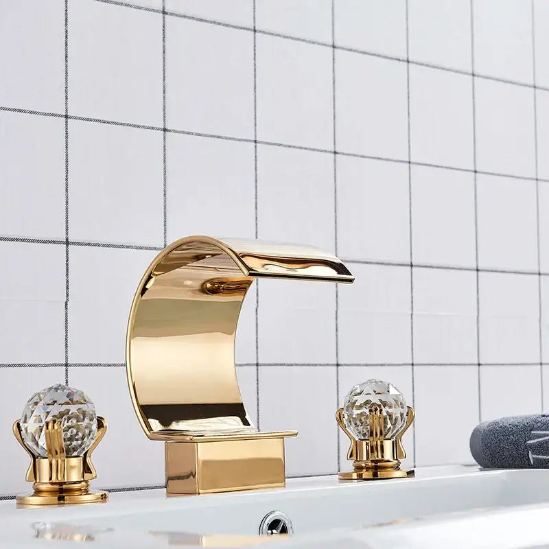 Elegant gold-toned waterfall basin faucet set with crystal knob handles for a luxurious bathroom tap installation
