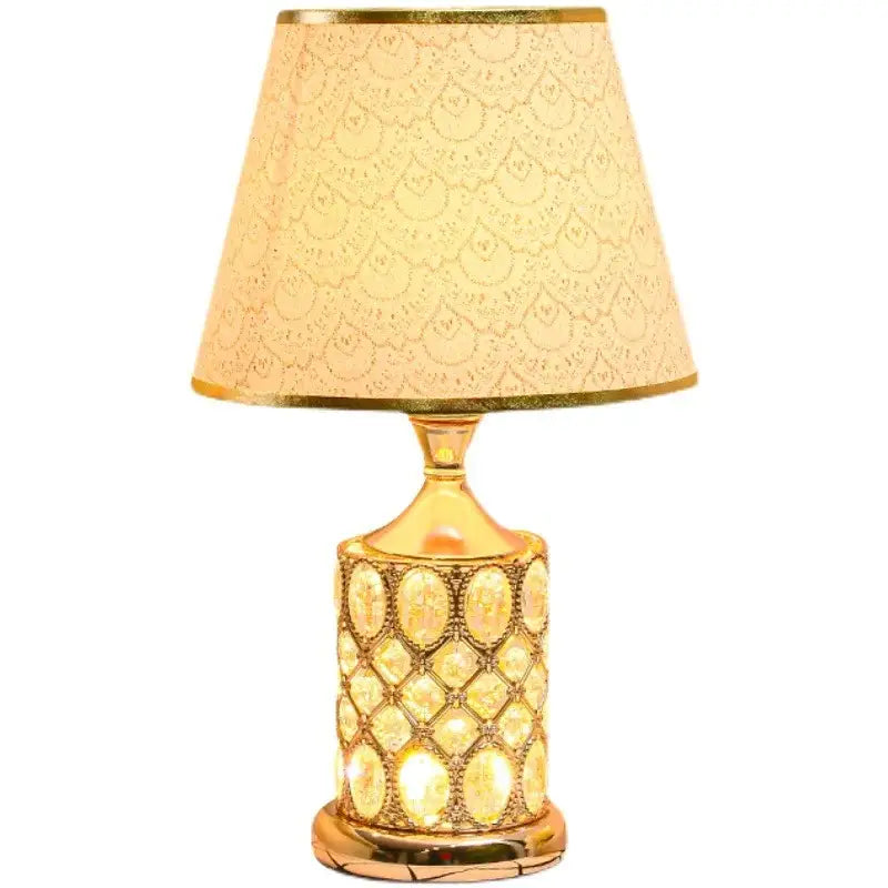 Elegant gold crystal table lamp with a beaded base and off-white shade featuring gold peacock feather decorbites crystal table