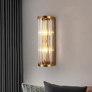 Elegant gold crystal wall lamp featuring cylindrical design with vertical crystal rods and warm glowing lights for decorbites
