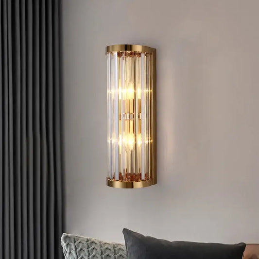 Elegant gold crystal wall lamp featuring cylindrical design with vertical crystal rods and warm glowing lights for decorbites