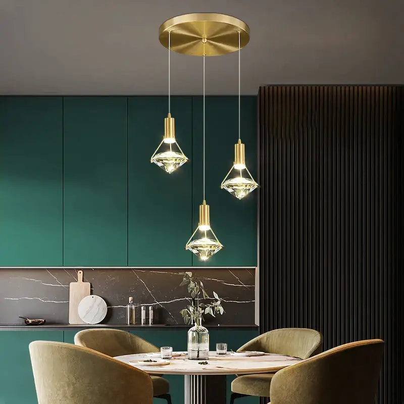 Three elegant gold diamond crystal pendant lights with faceted shades hang from a circular ceiling fixture