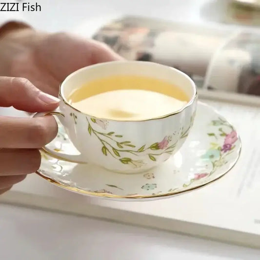 A delicate white porcelain teacup and saucer set with pastel floral patterns and an elegant gold flower rim decorbites saucer set