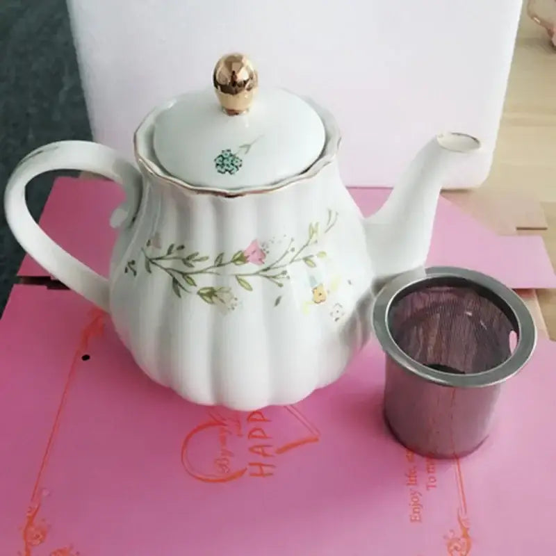 White ceramic teapot with floral design and gold accents featuring a golden knob from decorbites elegant gold flower saucer set decor