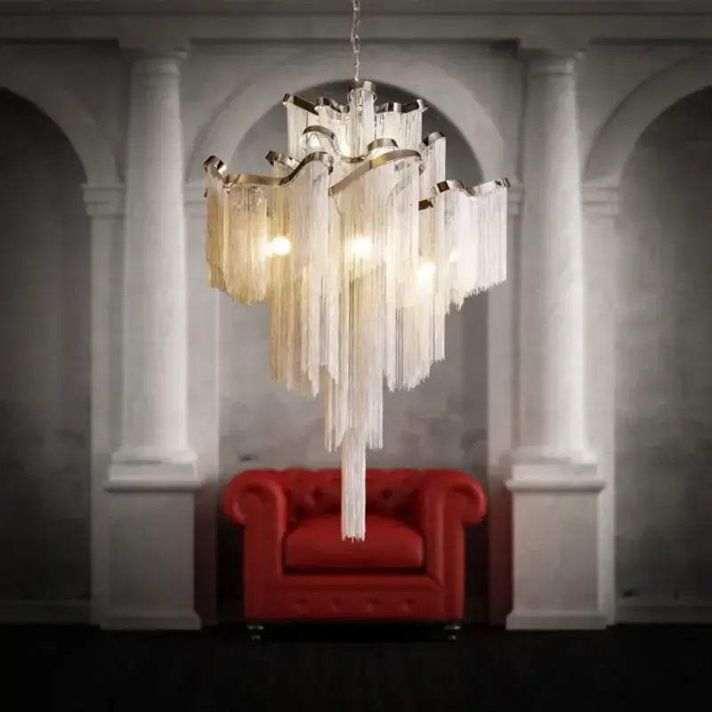 Elegant gold decorbites fringed chandelier with translucent glass fringes and metallic frame above red leather chair