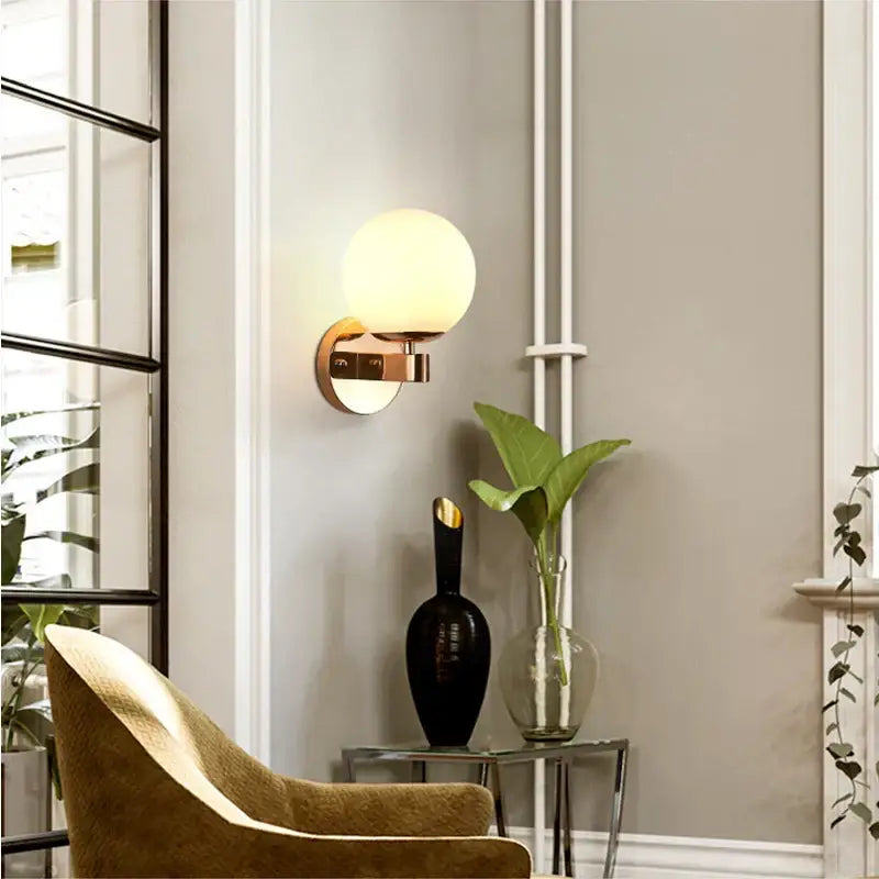 Elegant gold iron wall lamp with frosted spherical glass shade and polished brass base for bedroom decorbites iron wall lamp