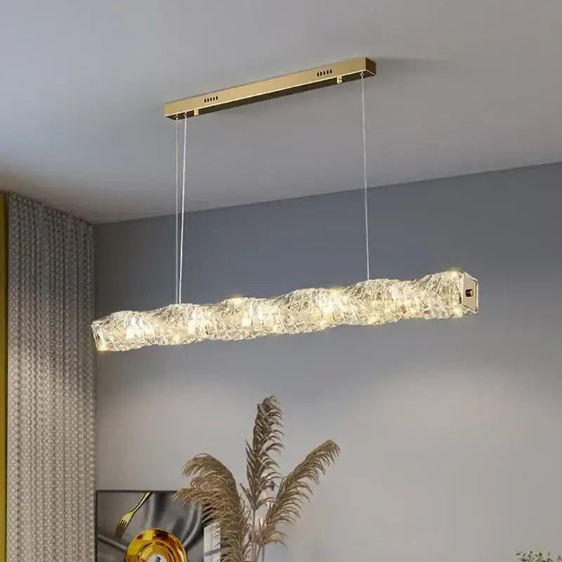 Elegant gold led crystal rectangular chandelier with textured crystal body emitting warm light for dining room