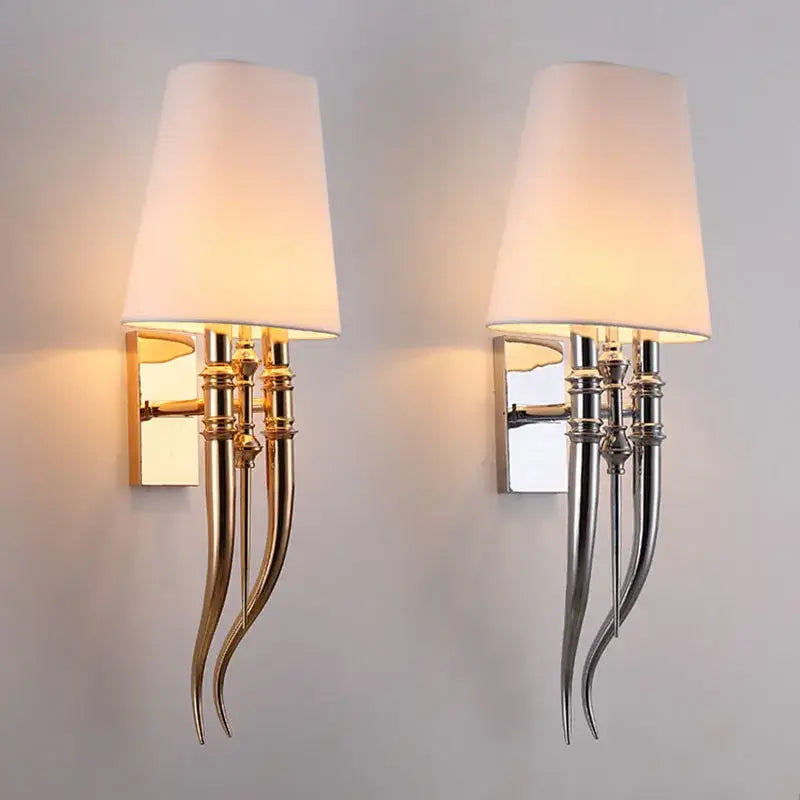 Pair of elegant gold and silver iron claw horn wall sconces with curved metallic arms and white fabric shades for bedroom
