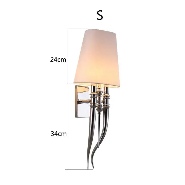 Elegant silver-toned iron claw horn wall sconce with off-white fabric shade and curved metallic arms for bedroom use