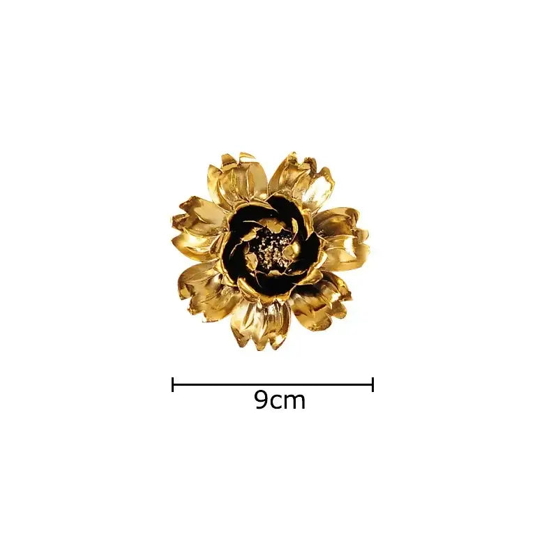 A golden flower-shaped brooch with a black center and sparkling details for decorbites elegant porcelain wall ornaments