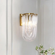 Elegant gold wall lamp with twisted crystal shade featuring a gold metal frame and cascading clear glass tubes for bedroom