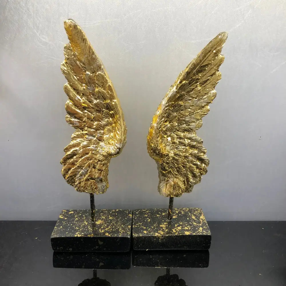 Elegant golden angel wings resin sculpture with detailed feather textures mounted on black marble bases for decor