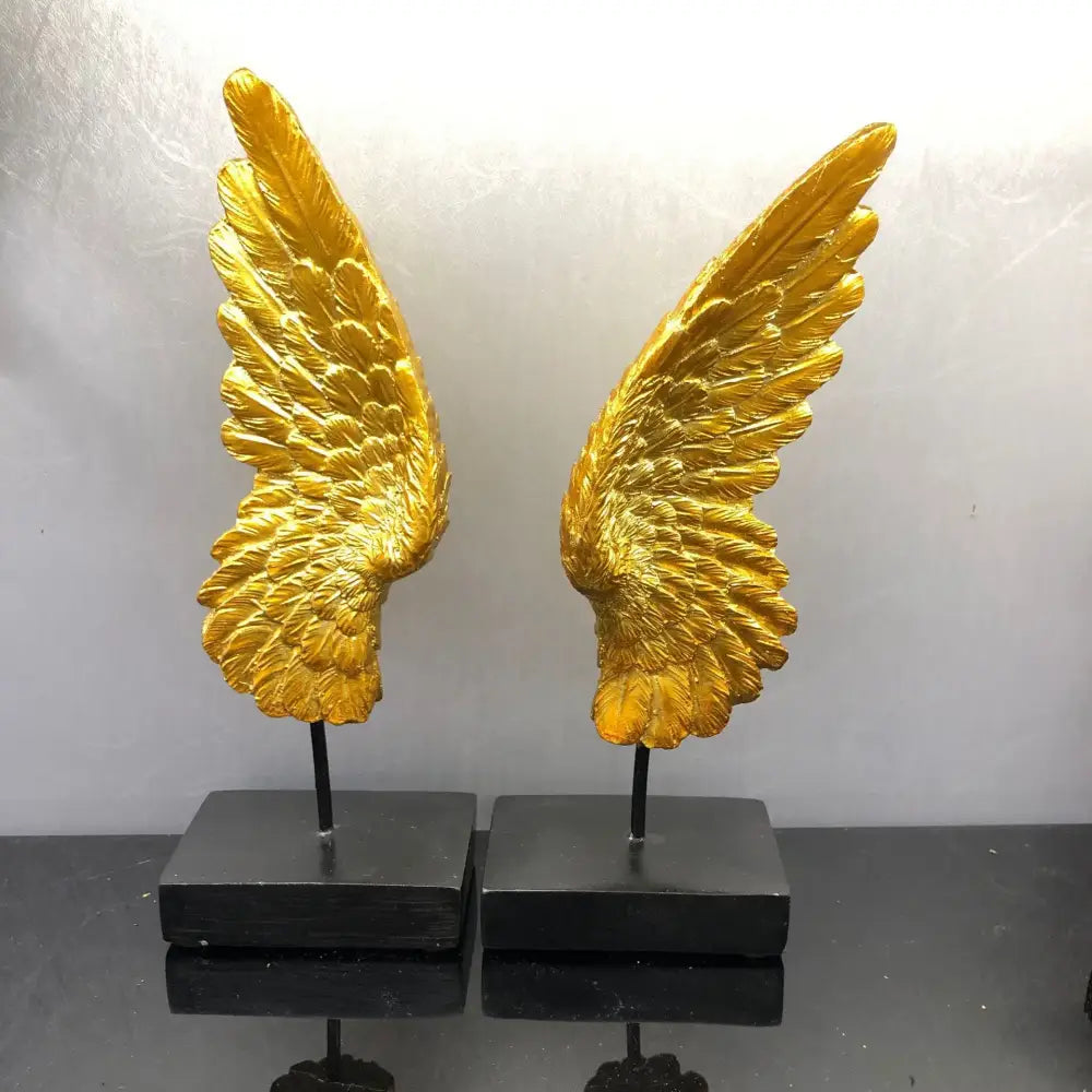 Elegant golden angel wings resin sculpture with intricate feather details mounted on sleek black bases for living room decor