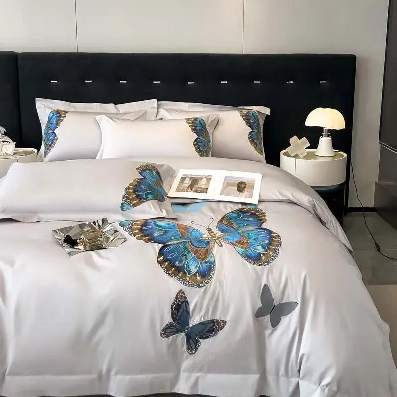 White satin bedding set with intricate blue and gold decorbites butterfly embroidery and subtle gray accents