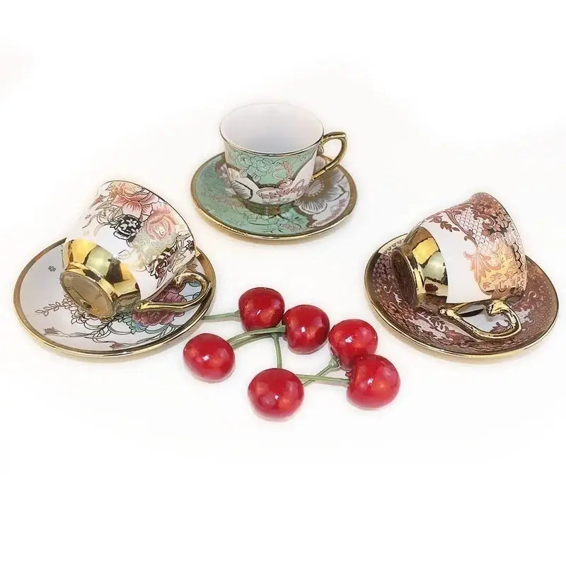 Three ornate hand painted flower ceramic coffee cups with gold rims and matching saucers for kitchen dining use