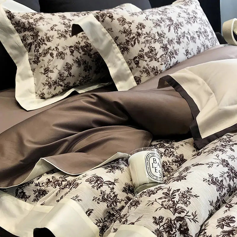 Cream-colored satin pillowcases with dark brown floral embroidery and piping in elegant egyptian cotton bedding sets