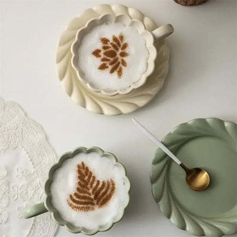 Elegant lace ceramic cream-colored coffee cup with scalloped rim filled with frothy latte and matching saucer set