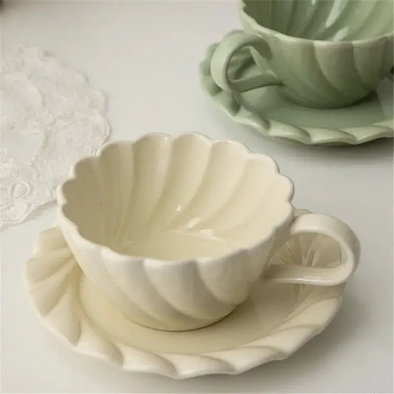 Elegant lace ceramic coffee cup and scalloped saucer set in cream with a delicate shell-like design for dining room use