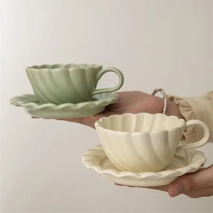 Elegant lace ceramic coffee cup and saucer set in pastel green and cream porcelain with scalloped rim for dining room use